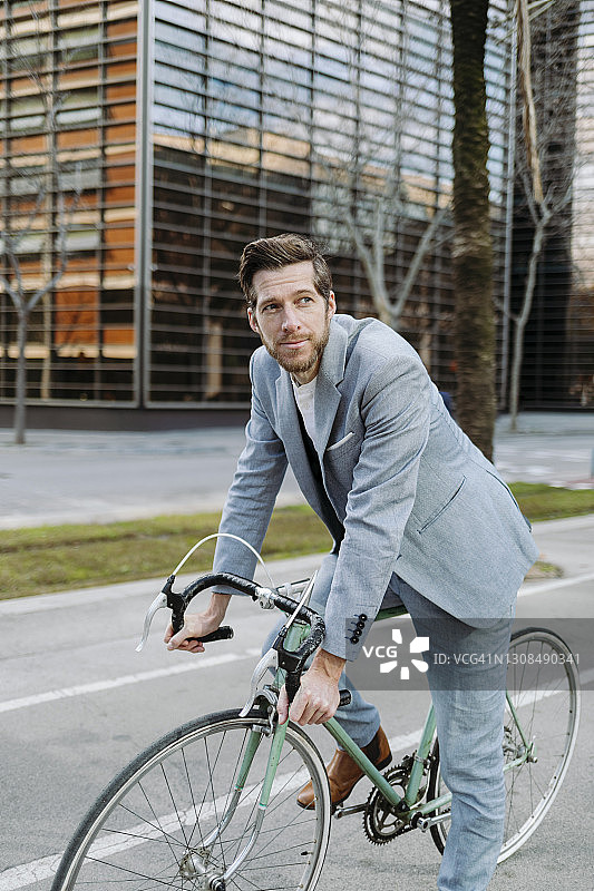 商人骑着自行车站在城市的人行道上图片素材