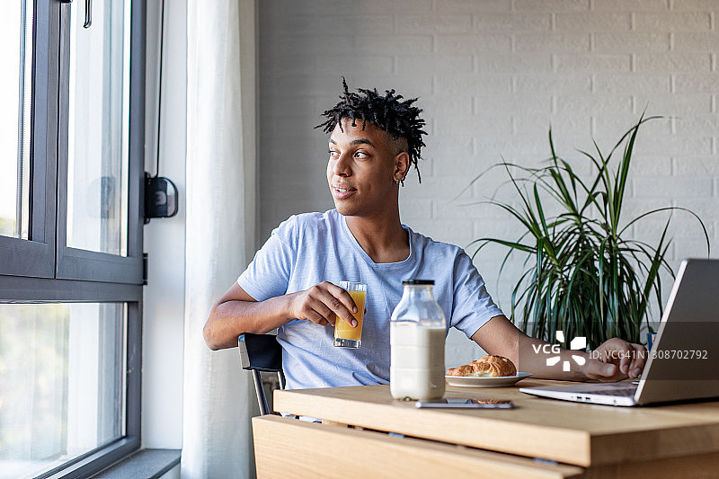 非裔美国人一边吃早餐一边用笔记本电脑图片素材