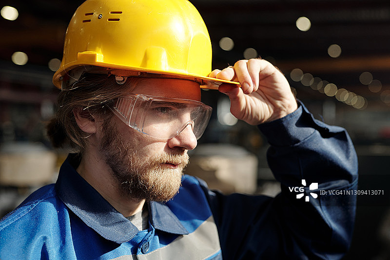 戴着安全帽和眼镜的年轻留胡子的男工程师或工厂工人图片素材