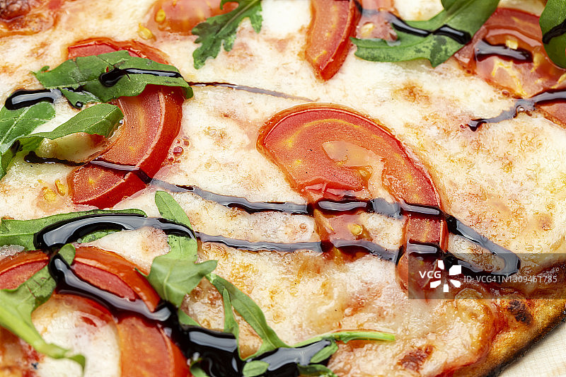 美味的披萨，包括西红柿，奶酪，芝麻菜，辣椒。图片素材