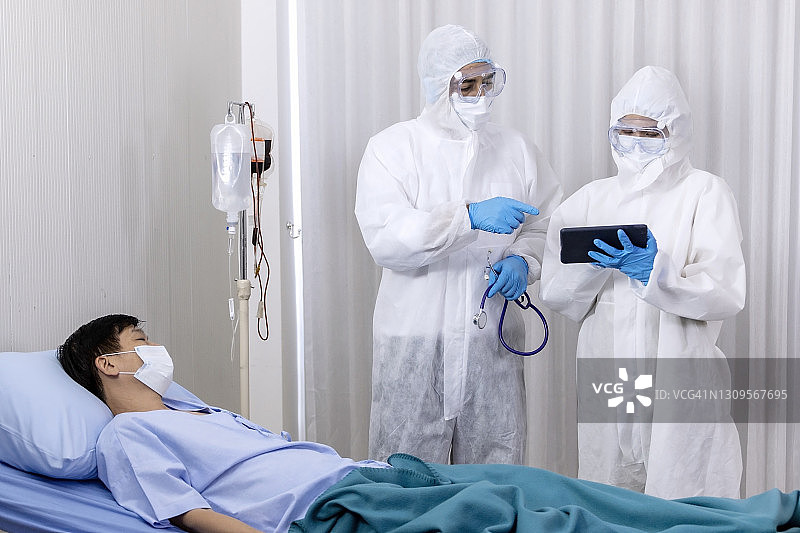 医学概念:一对医生穿着防护服在医院隔离区探望病人。图片素材