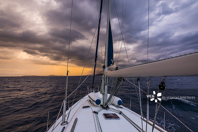 游艇在暴风雨与戏剧性的天空。日落时海面上出现了不可思议的雷云图片素材