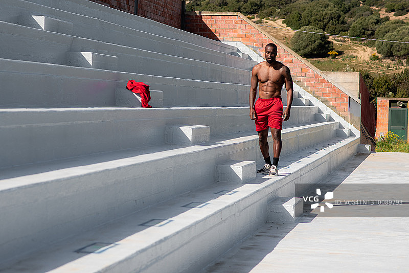 有吸引力的黑人肌肉运动员与运动服装和赤裸的胸部沿着楼梯走图片素材