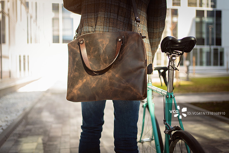 后视图一个不认识的商人与一个皮包和他的自行车图片素材