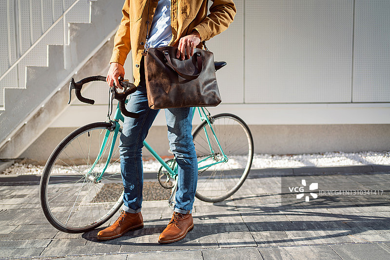 一个带着自行车和皮包的现代男人图片素材