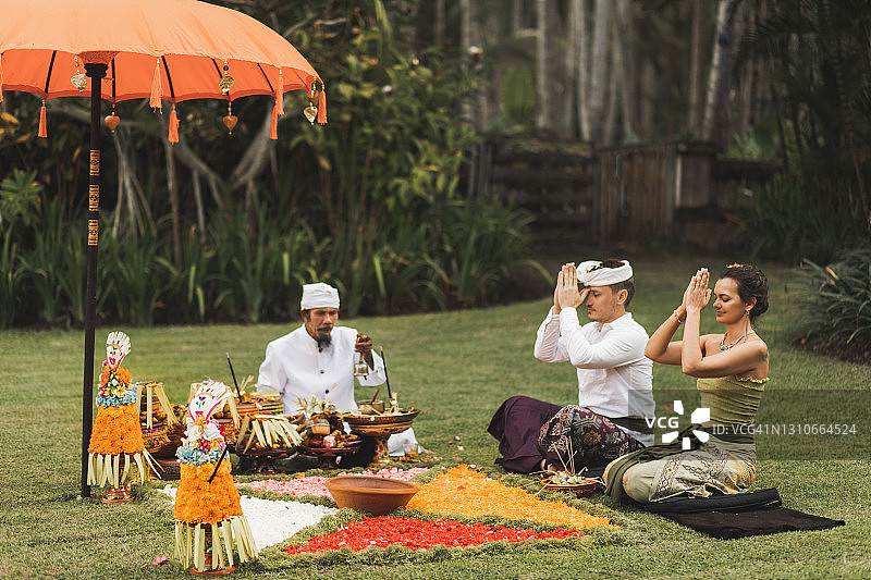 欧洲夫妇在巴厘岛传统的婚礼仪式上与巴厘岛僧人祈福图片素材