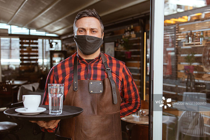 咖啡店门口戴着防护口罩的服务员图片素材