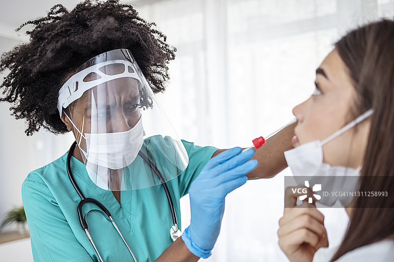 医生穿着防护服从年轻女子身上取鼻拭子测试图片素材