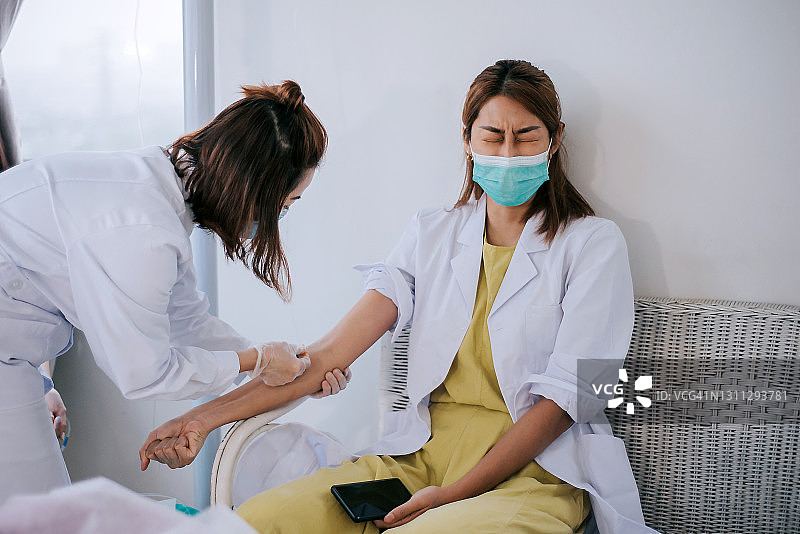 亚裔华人女性在诊所准备由护士进行手部静脉检查图片素材