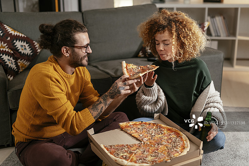 幸福的夫妇在家吃披萨。库存图片图片素材