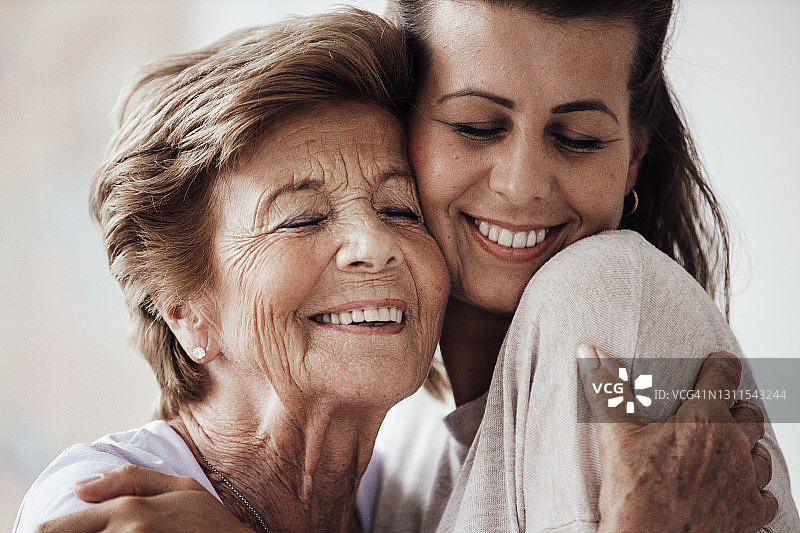 快乐的年轻女子和奶奶在家里互相拥抱图片素材