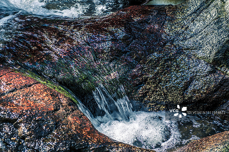 清澈的水流沿着覆盖着苔藓的岩石在瀑布。日本志贺里托御溪那瀑布图片素材