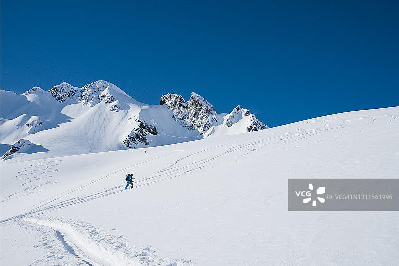 一个女人从白雪覆盖的冰川上滑向山顶图片素材