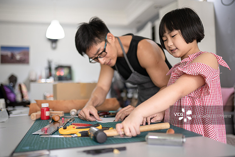 亚洲华人男子教他的女孩如何用皮革裁剪图案图片素材