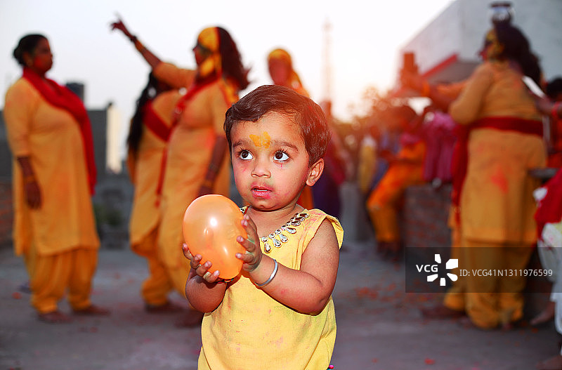 胡里节上，小女孩手拿气球，一些妇女在她身后跳舞图片素材