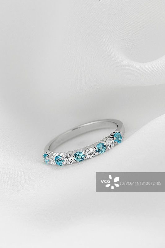 银色女性结婚钻石戒指在白色和蓝色的背景图片素材