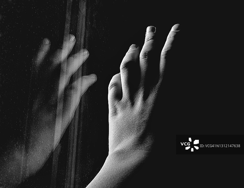 年轻女子的手映在玻璃上，黑白相间图片素材