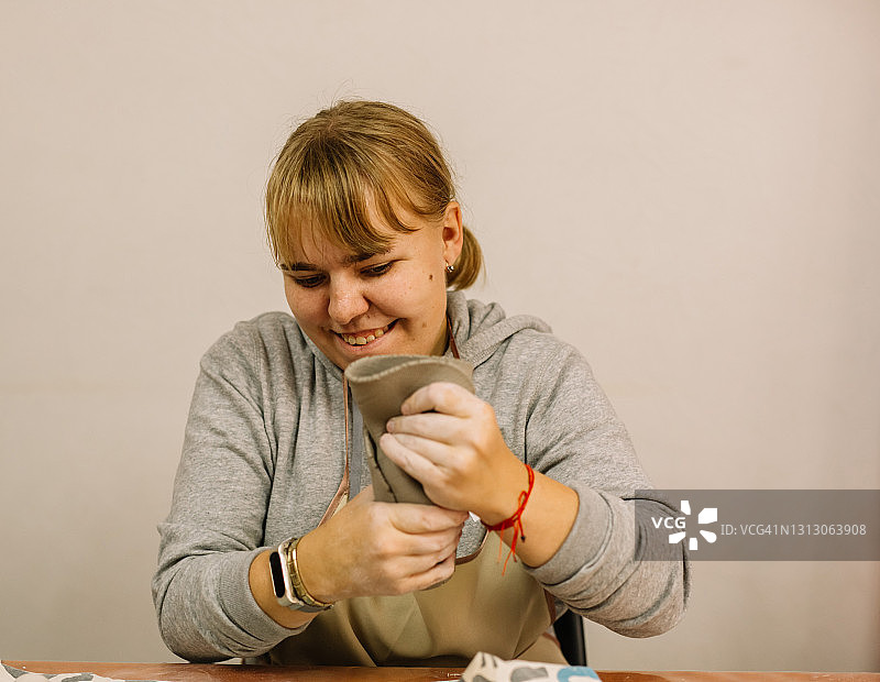 一位年轻的妇女在陶器作坊里用粘土制作陶器。图片素材