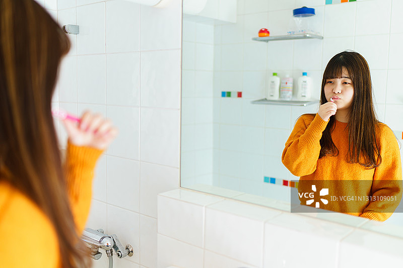 一个年轻女子在浴室里刷牙图片素材