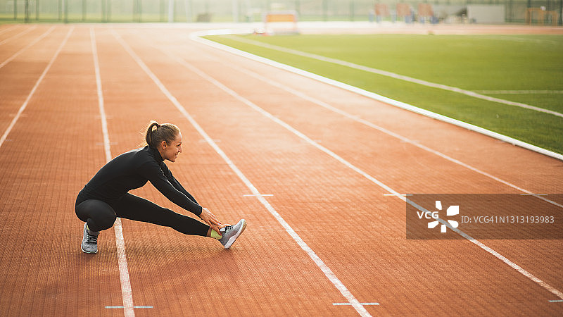 女人伸展和热身跑步前在田径体育场。存放拷贝空间图片素材