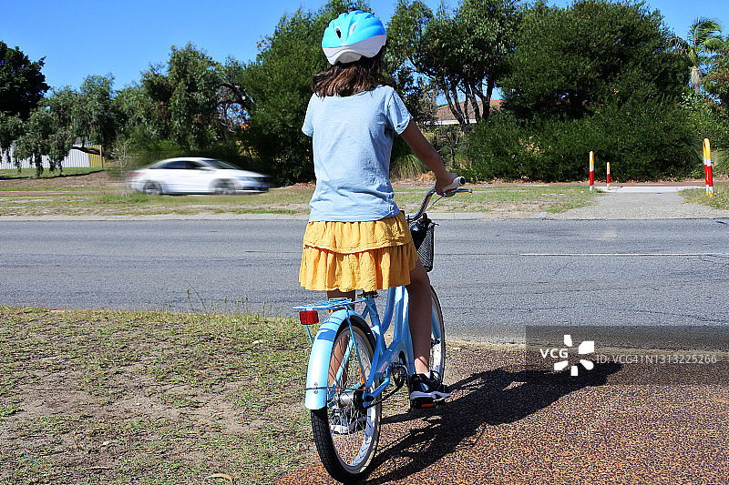 年轻的女孩骑着自行车试图自己穿过城市的主要道路图片素材
