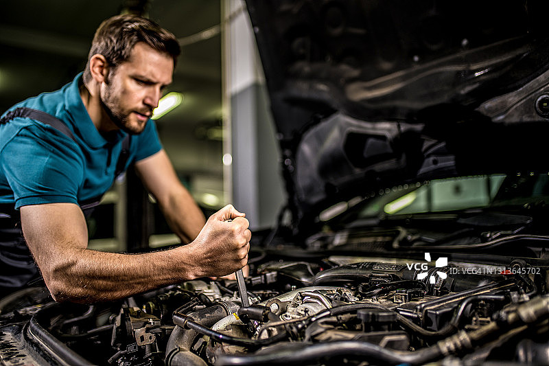 汽车修理工在汽车车间修理汽车发动机。图片素材