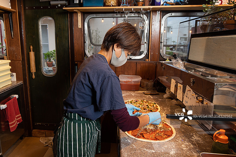 一个妇女在她的家庭生意中准备披萨图片素材