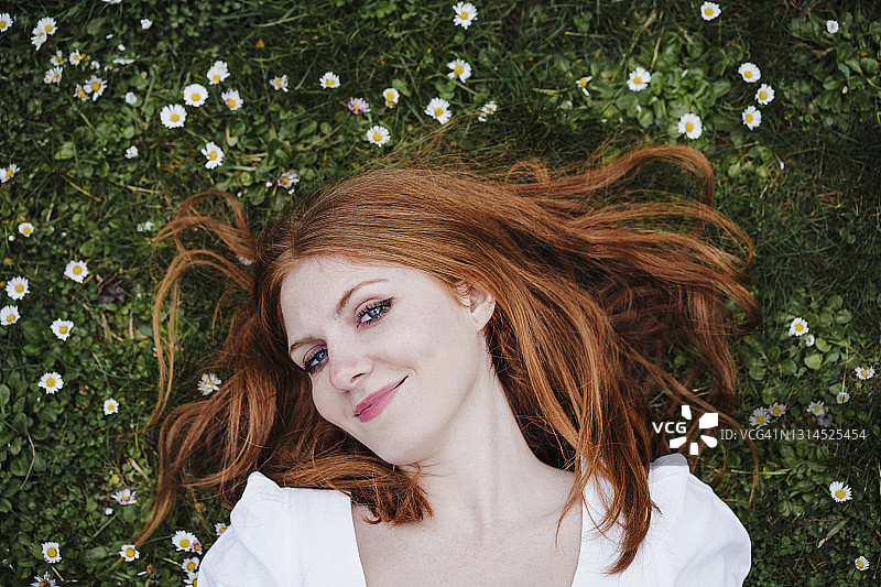 红发女人微笑着躺在草地上图片素材