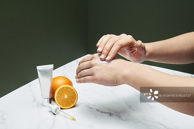 女人用护手霜美容产品和橘子水果桌上图片素材