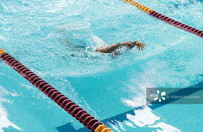 在奥林匹克游泳池游泳的年轻运动员。图片素材