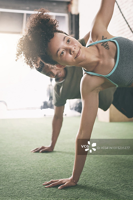 两个运动的年轻人在健身房做侧平板支撑图片素材