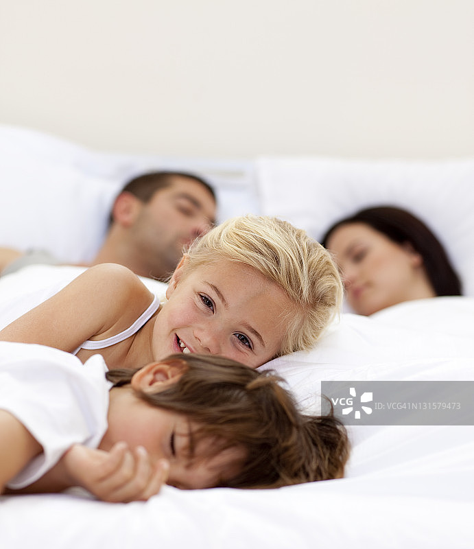小女孩在微笑，她的父母和弟弟睡觉图片素材