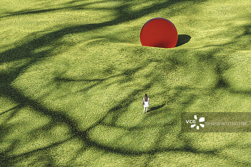 一个女人在梦幻草地上走向巨大的玻璃球图片素材