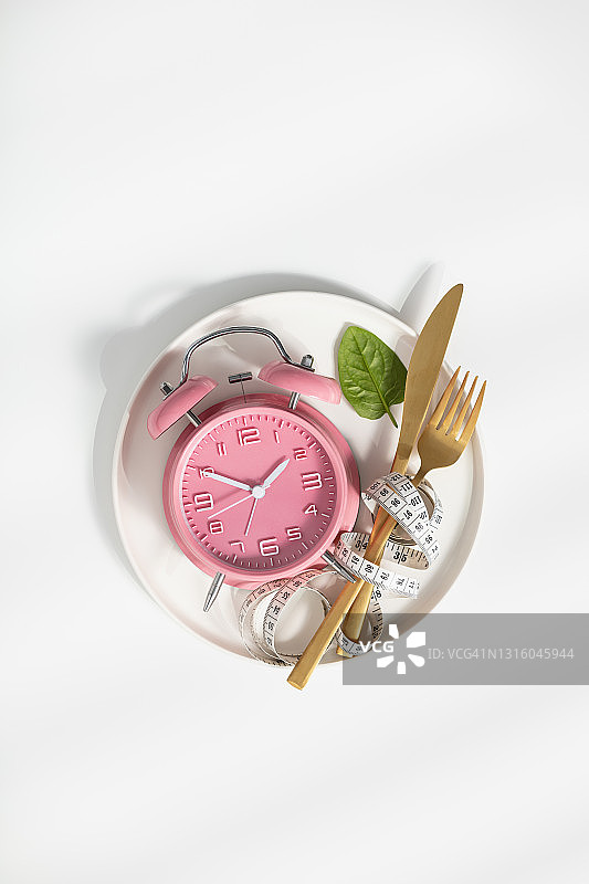 用餐具、卷尺和闹钟在白色背景上构图。饮食概念图片素材