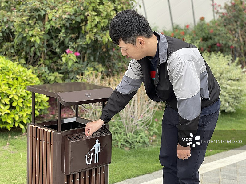 一个年轻的中国男子正在扔烟头和垃圾。图片素材