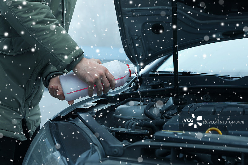 在室外给汽车散热器加防冻剂的人，特写图片素材