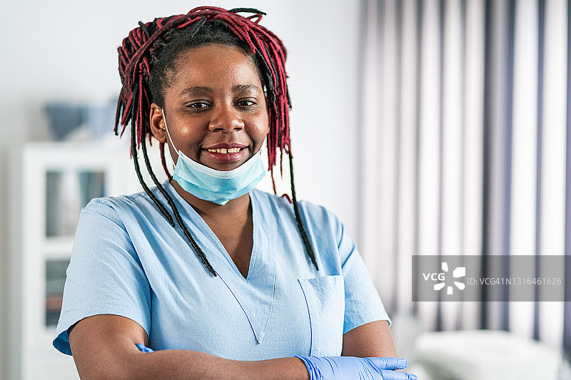在冠状病毒流行期间，中年非洲女医生双臂交叉站在医生办公室图片素材