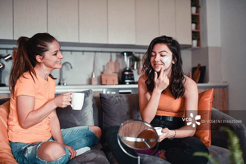 可爱的女性在家里喝咖啡和谈论护肤霜图片素材
