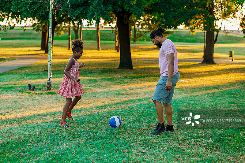 一个快乐的非裔美国人家庭正在草地上玩足球。图片素材
