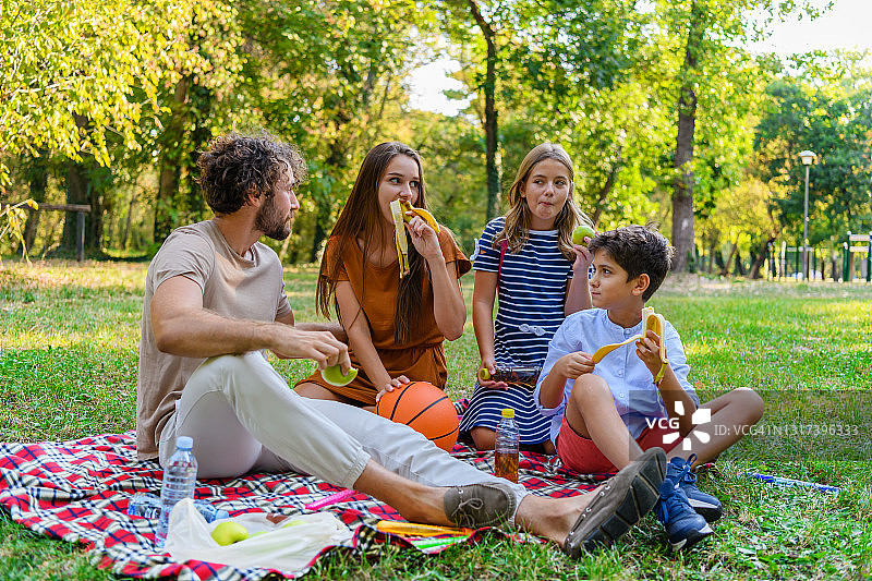 一个幸福的家庭正在草地上野餐。图片素材