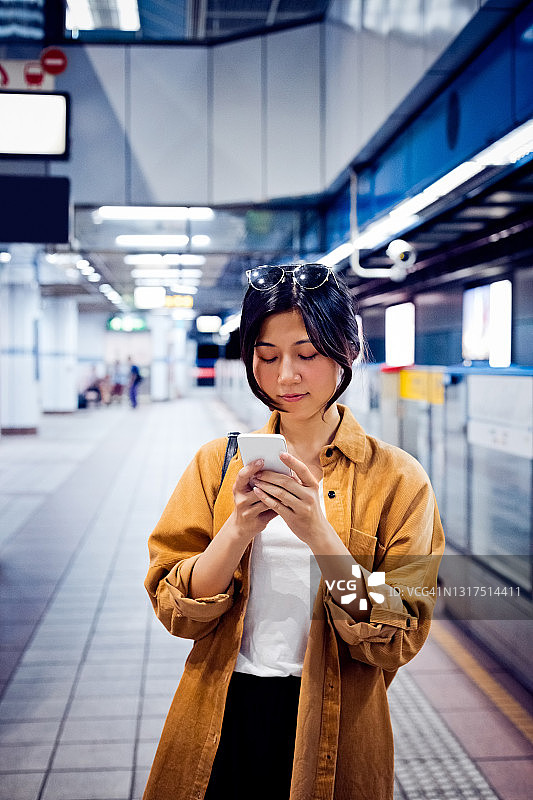 一名女子在地铁站台上使用智能手机图片素材