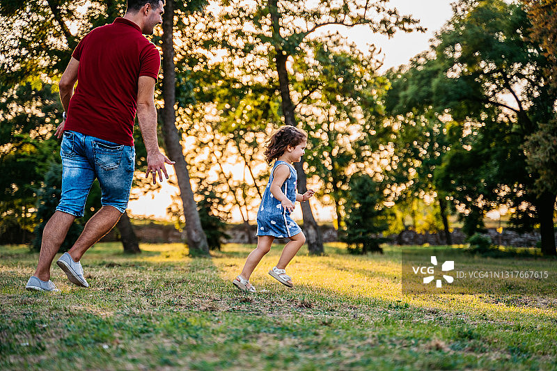 父亲和女儿在公园里跑步图片素材