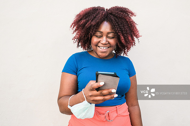 曲线非洲女人看着她的智能手机-技术和生活方式的概念图片素材