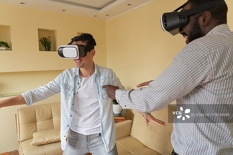 一个长胡子的美国黑人和他的朋友正在用虚拟现实模拟器玩游戏。图片素材
