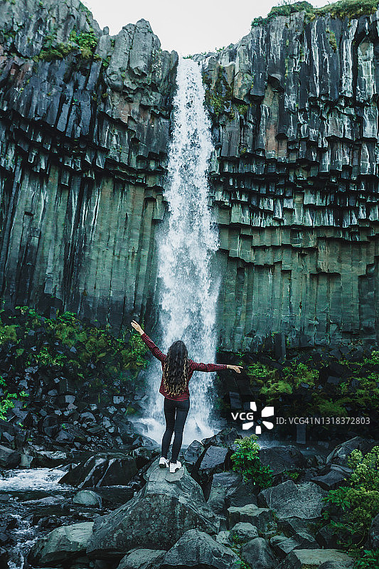 快乐的女人享受附近的冰岛著名的瀑布。后面的观点。图片素材