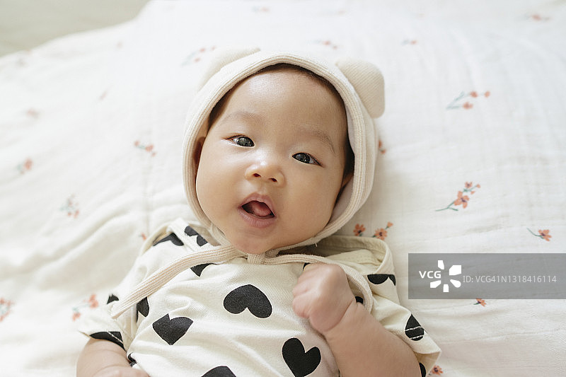 特写肖像可爱的快乐的面部表情亚洲新生儿在舒适的床上图片素材