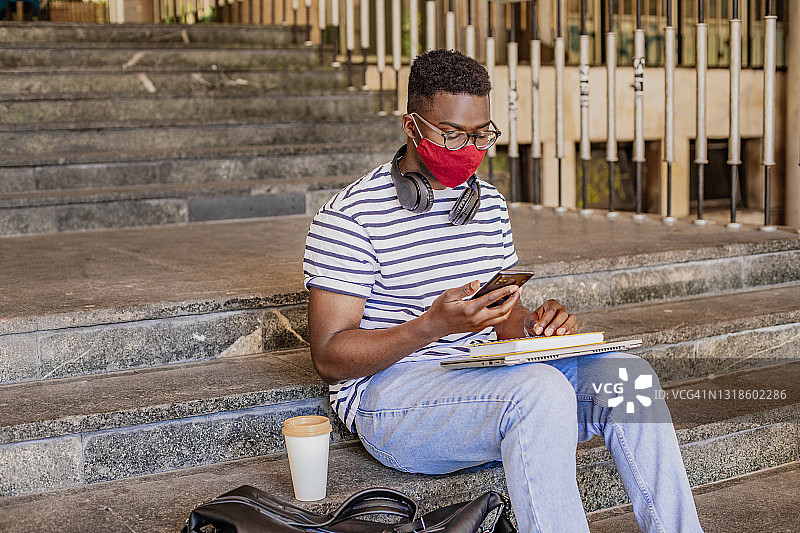 非裔美国大学学生戴着防护口罩使用手机图片素材