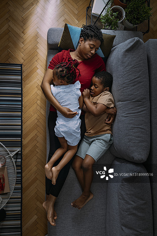 俯视图美丽的母亲与小女儿和儿子睡在沙发上图片素材