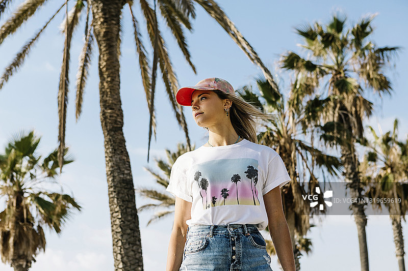 在阳光明媚的日子里，一名女子站在棕榈树下图片素材