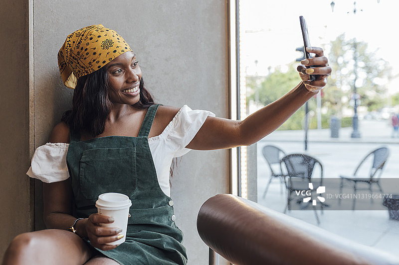 一名女子在咖啡馆用智能手机自拍图片素材
